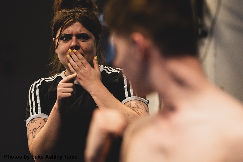 Photograph of a woman looking scared at a man blurred in the foreground