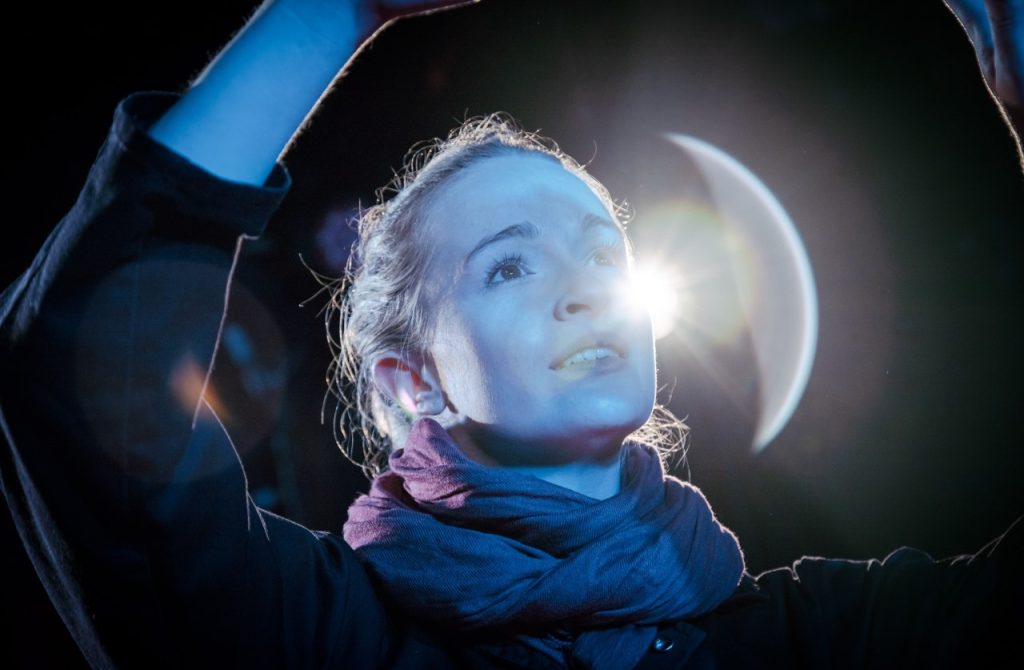 Cold War Plays at Alma Theatre Bristol - A woman looks away from the camera towards something unseen. She is backlit with a bright light, almost like a moon