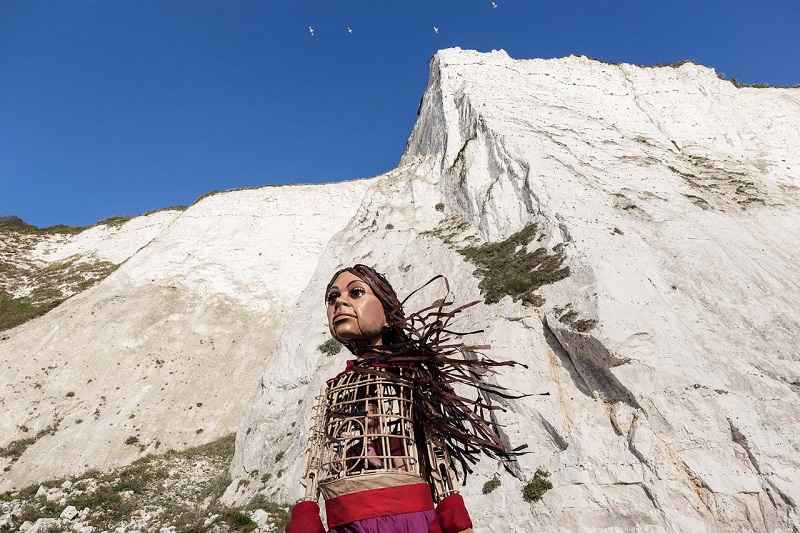 Little Amal Walk Bristol - A photo graph of Little Amal puppet in front of snowy mountains