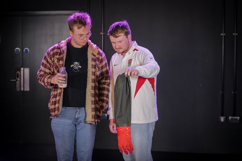 Photograph of two men. Both are looking at what appears to be an udder with confusion and concern