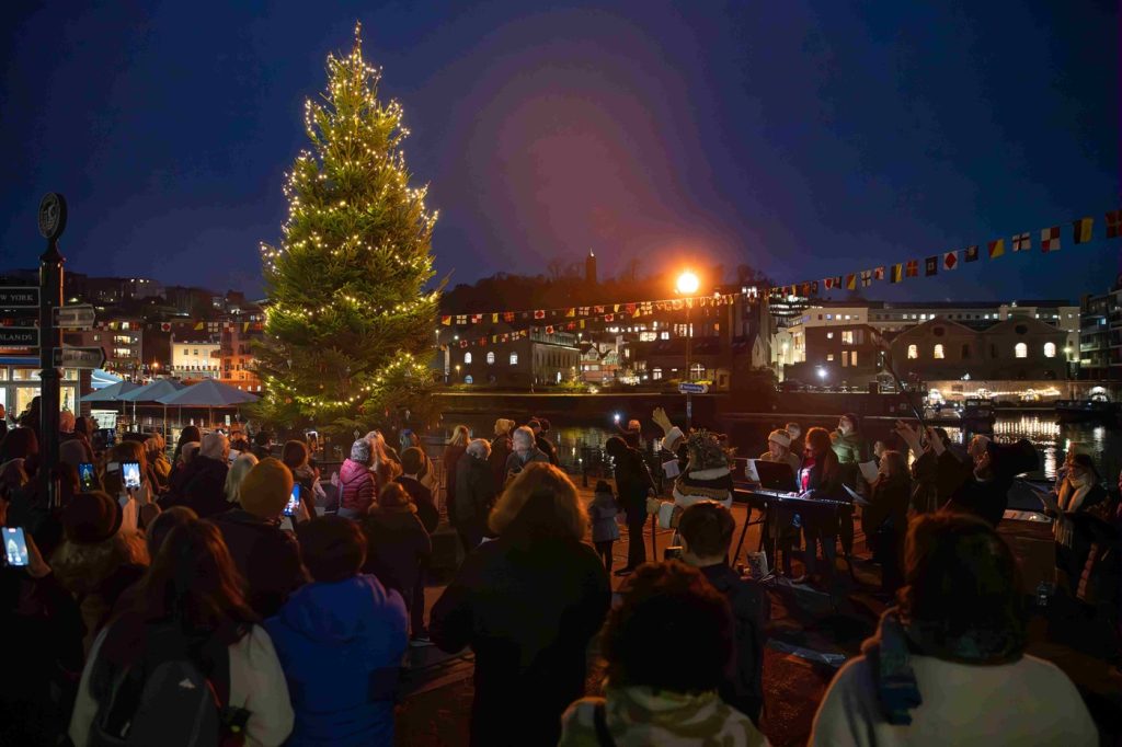 SS Great Britain Tree and Golden Ticket Programme - A photograph of people gathered around a large, brightly lit Christmas tree at night